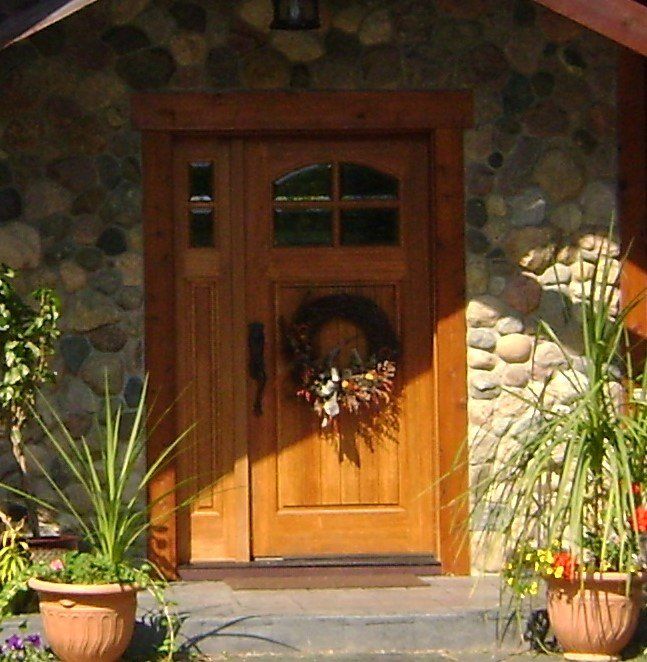 A wooden door with a wreath on it in front of a stone wall