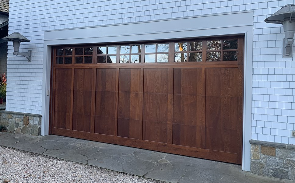 A wooden garage door is sitting in front of a white brick building.