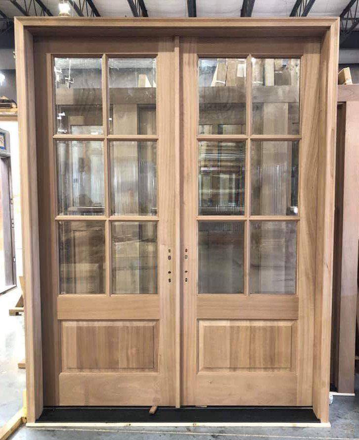 A pair of wooden doors with glass panels are sitting on a concrete floor.