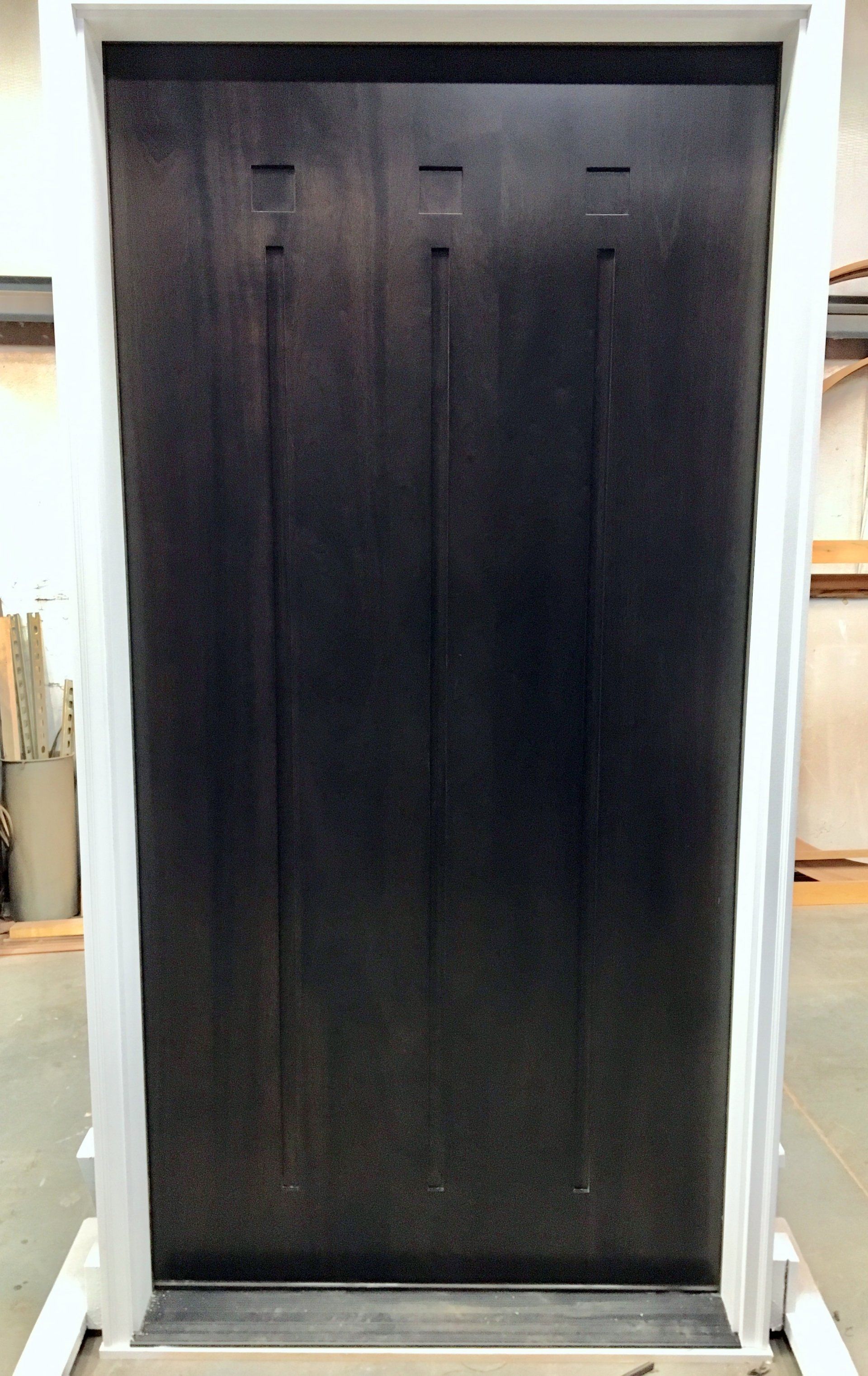 A black door is sitting on a white stand in a room.