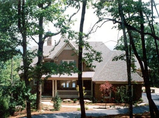 A house with a large porch is surrounded by trees