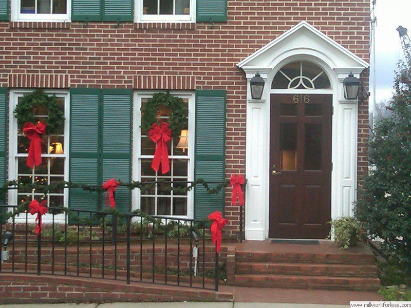 A brick house with green shutters and a brown door