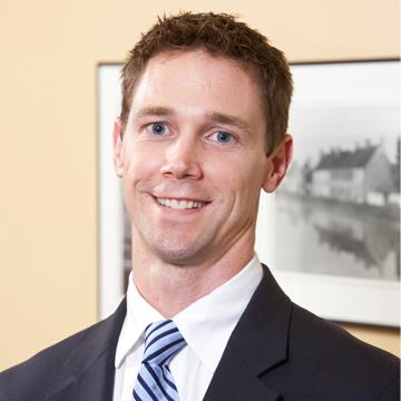 Smiling man in a dark suit and striped tie in an office setting