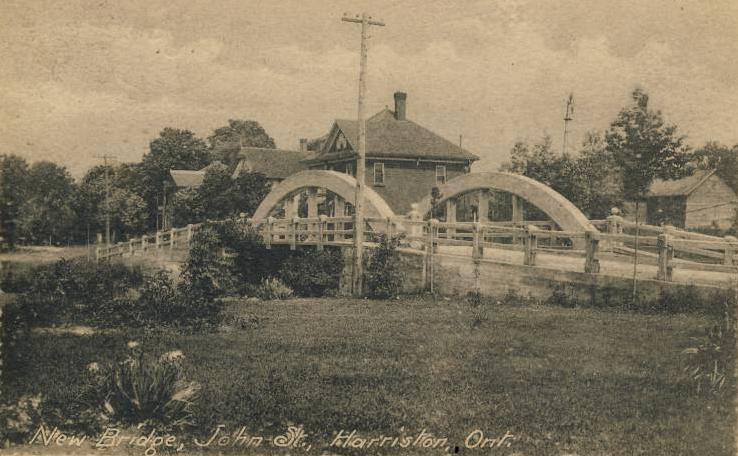 A black and white photo of a bridge with a house in the background