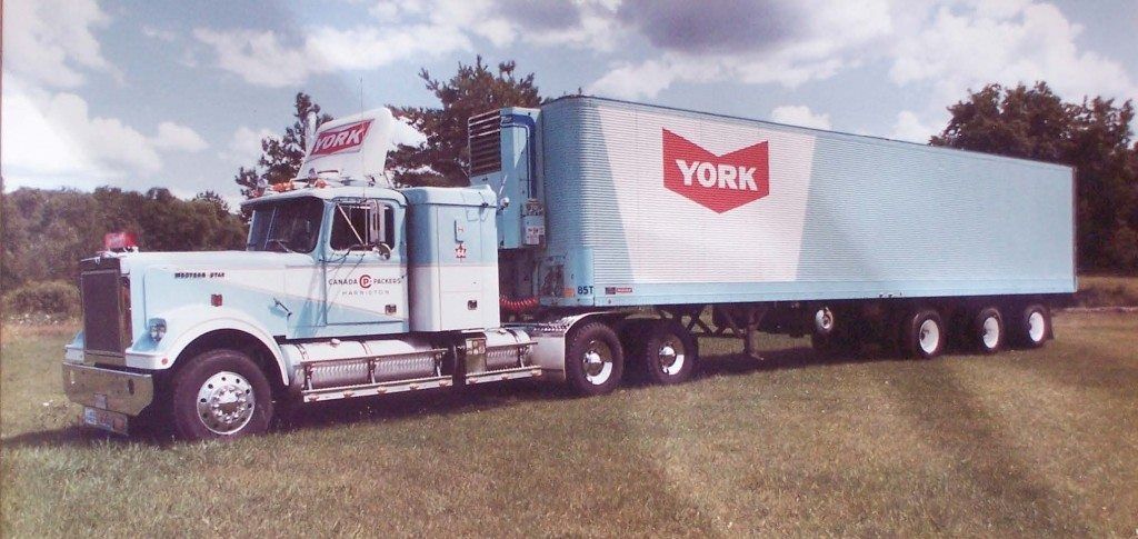 A york semi truck is parked in a grassy field