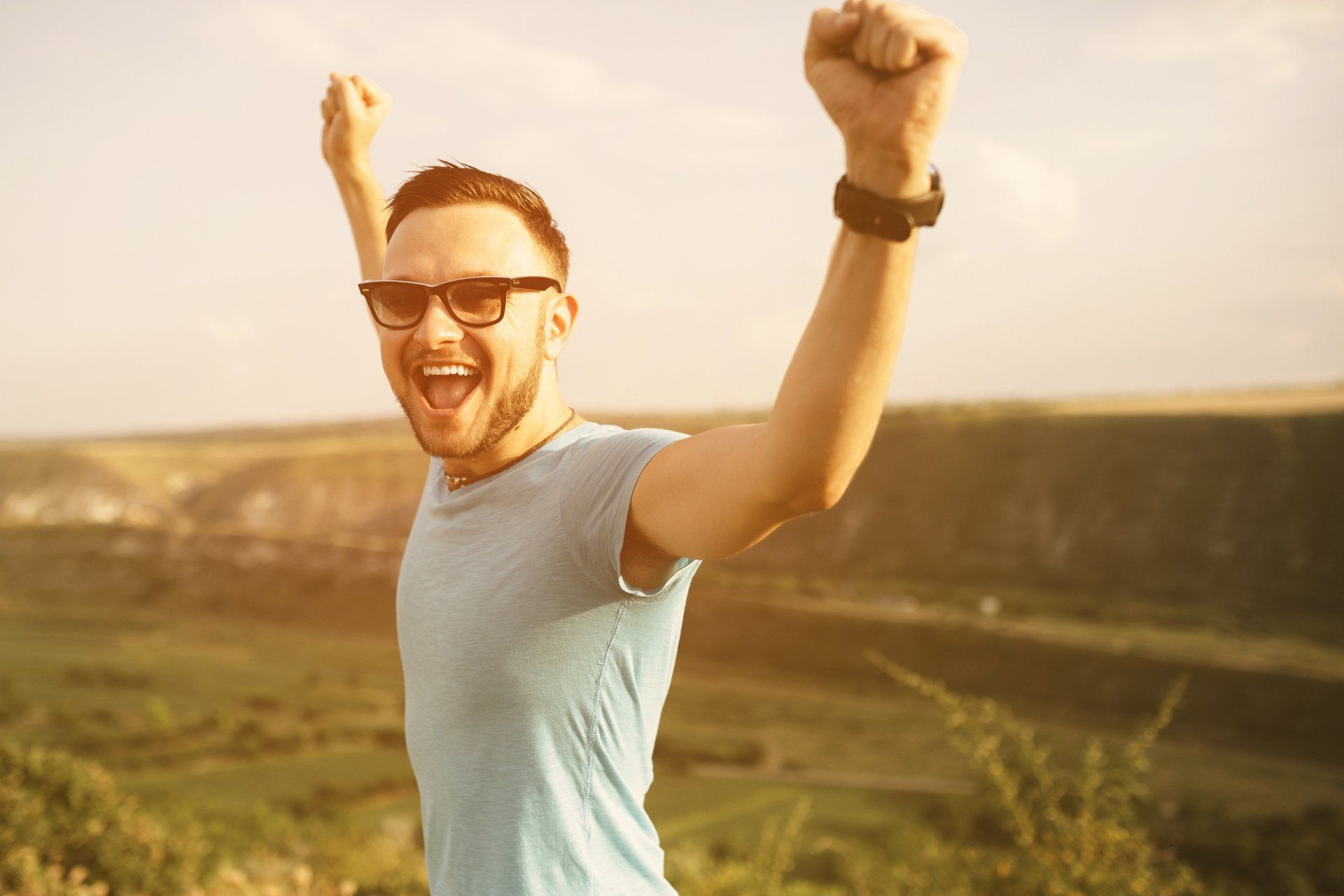 Coaching image showing a smiling man celebrating success with his arms raised