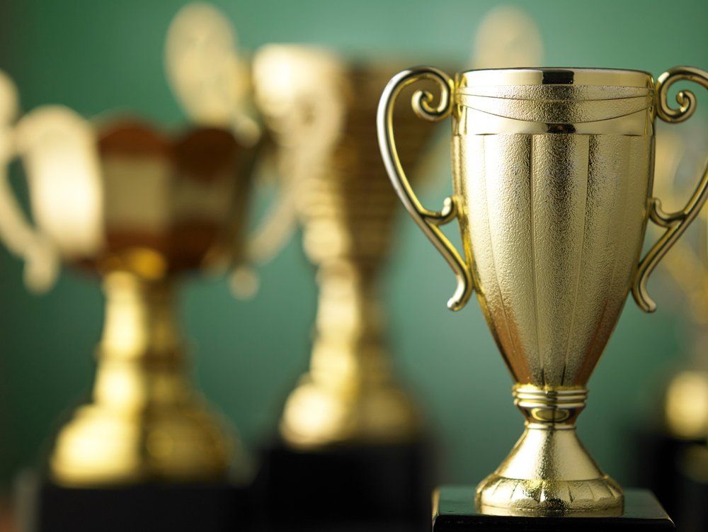 Several gold trophies are lined up in a row