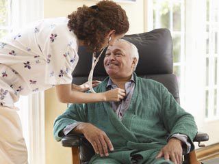 Worker listening to man's heart with stethoscope