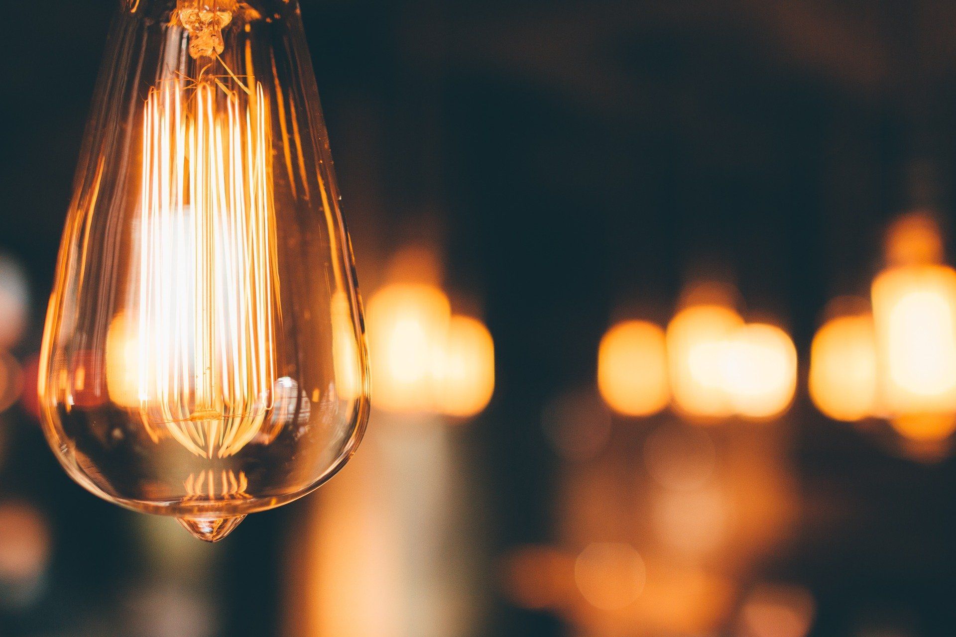 Nahaufnahme einer beleuchteten Glühbirne im Edison-Stil, im Hintergrund verschwommenes warmes Licht.