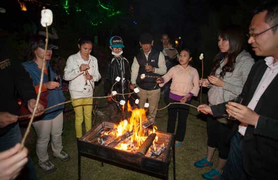 A group of people are roasting marshmallows over a fire.