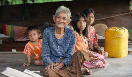 An elderly woman is sitting on the floor with three children.