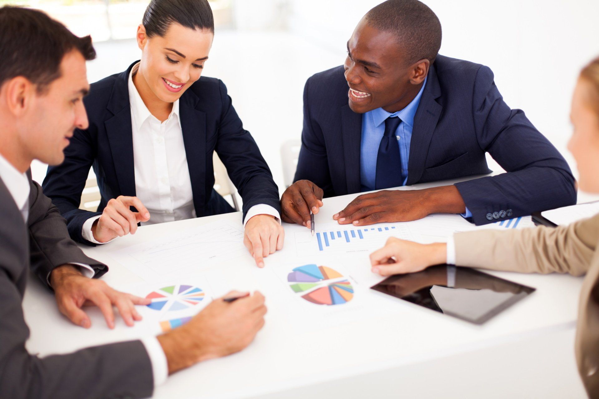 A group of business people are sitting around a table looking at charts.