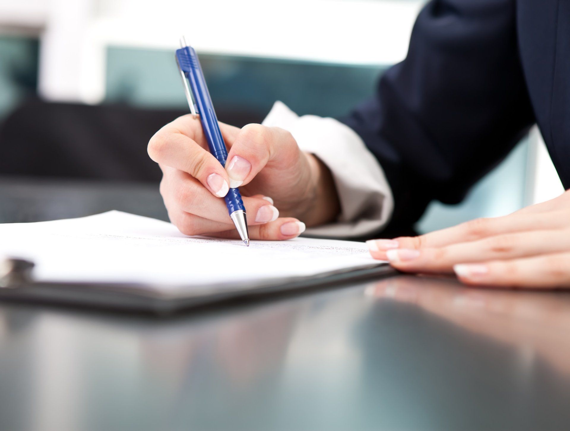 A woman is writing on a piece of paper with a pen.
