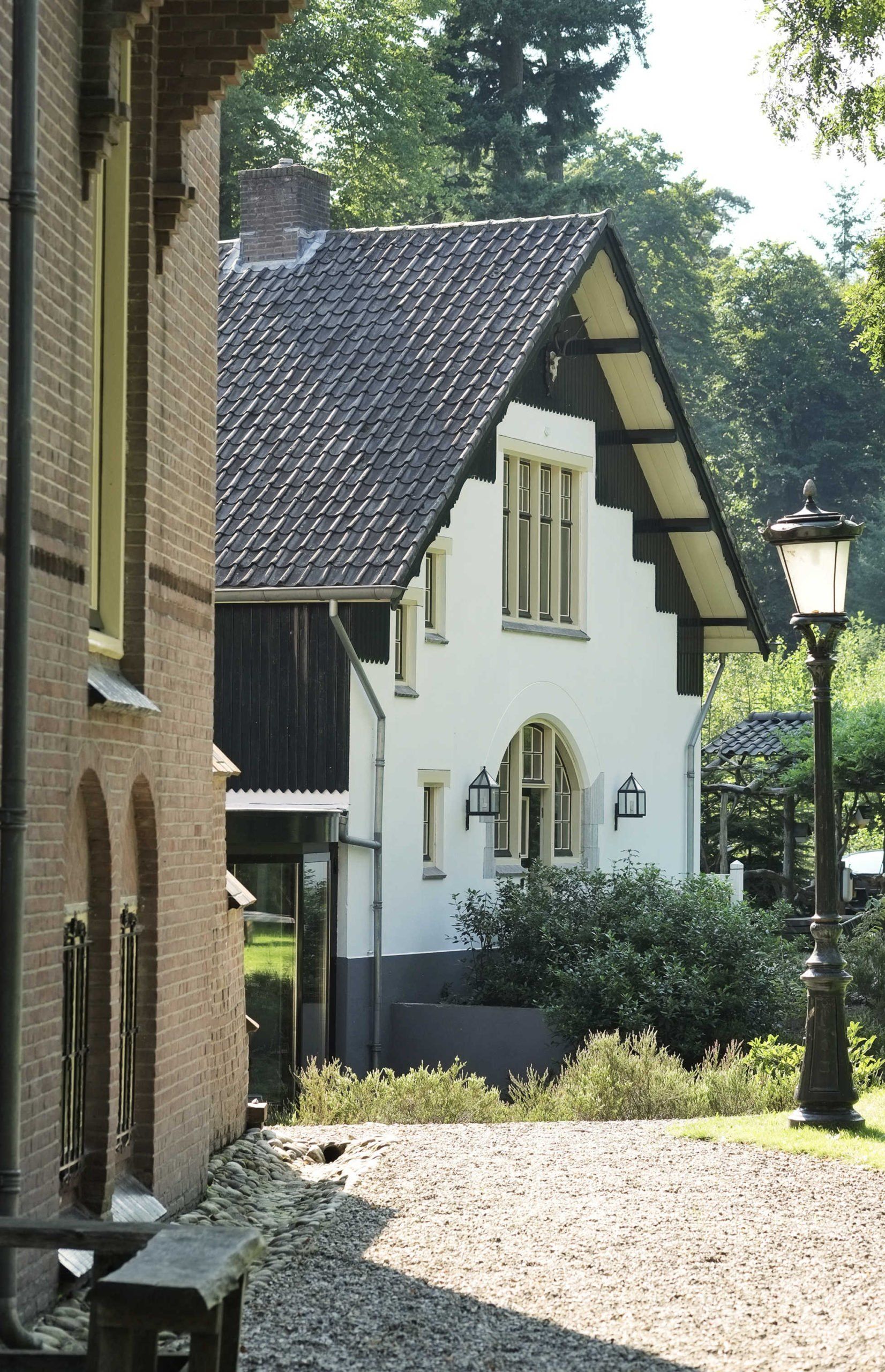 Naast een bakstenen gebouw staat een wit huis met een zwart dak