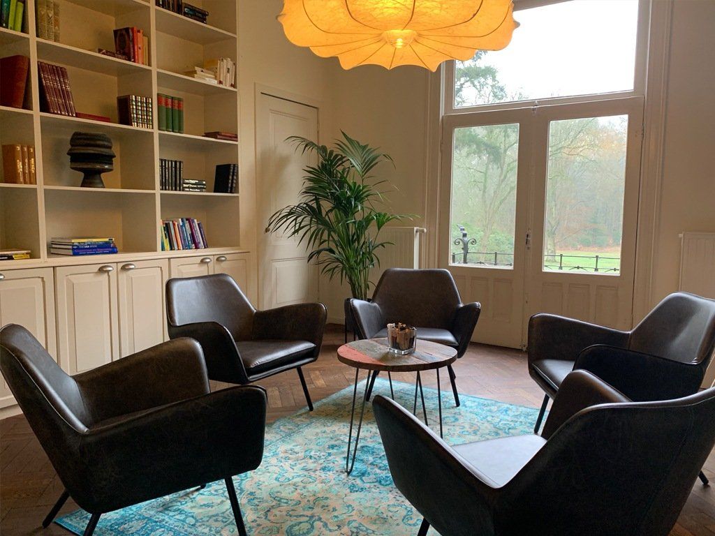 Een woonkamer vol stoelen en een tafel.