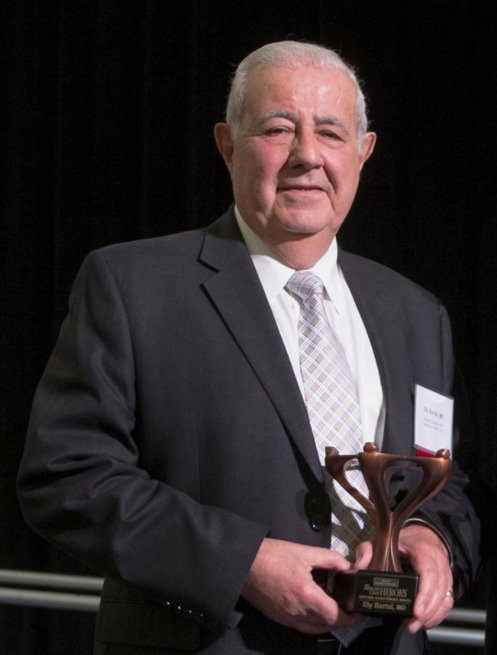 CEO and Medical Director Dr. Bartal holding Healthcare Heroes 2017 Lifetime Achievement Award from Wichita Business Journal