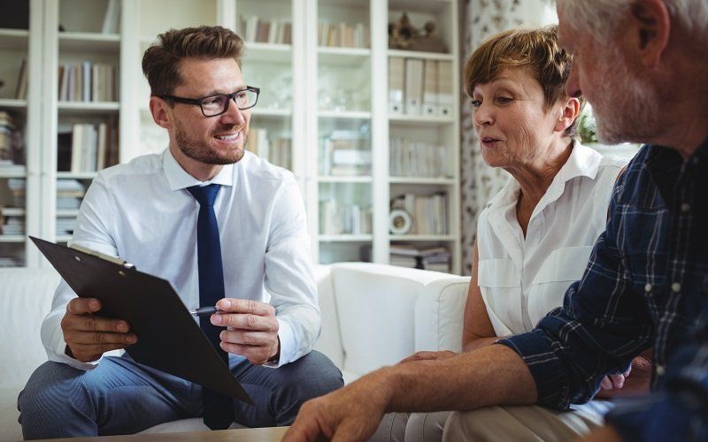 Three people in a bright office reviewing documents and discussing with a tablet open