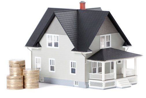house miniature next to stack of coins