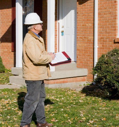 man in hardhat inspecting house