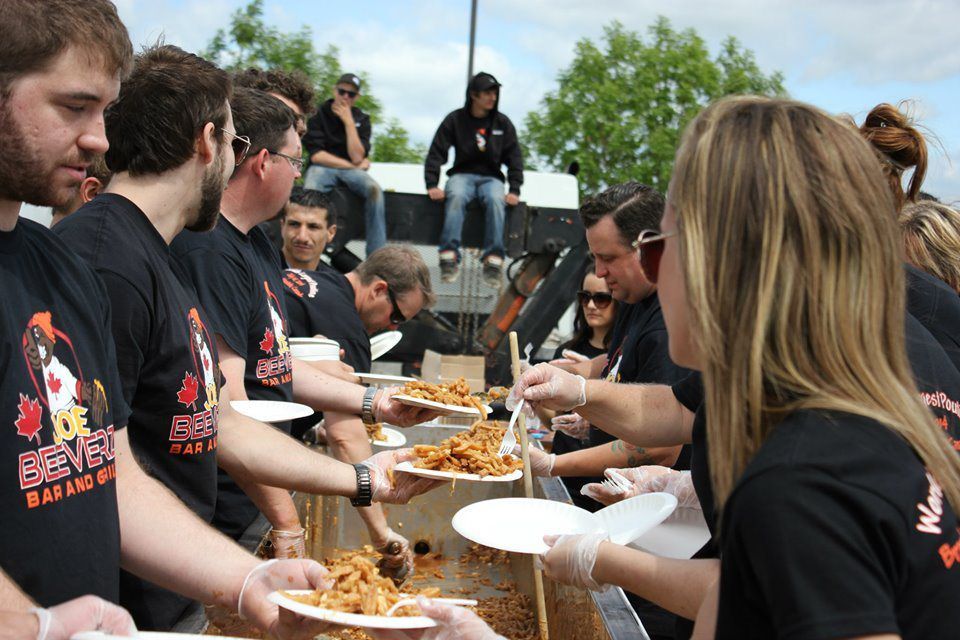 People serving food and eating at an outdoor community barbecue event