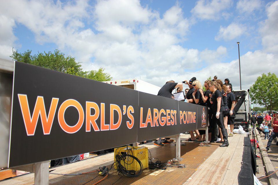 Crowd gathered on a bridge beside a giant black banner reading “WORLD’S LARGEST”