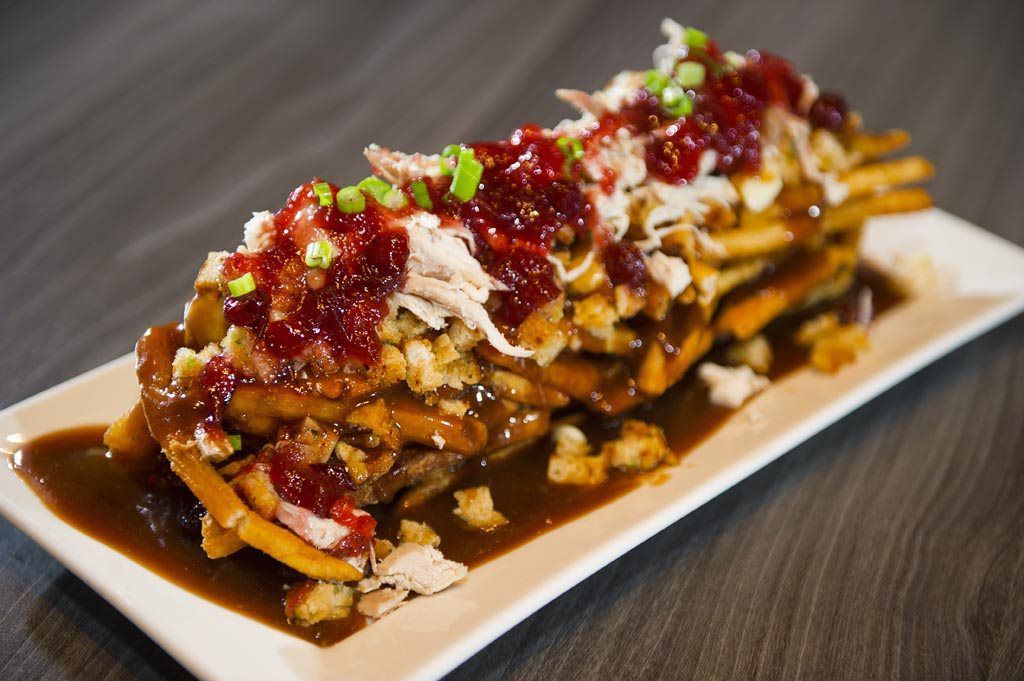 Loaded nachos topped with red salsa, melted cheese, and green garnish on a white plate