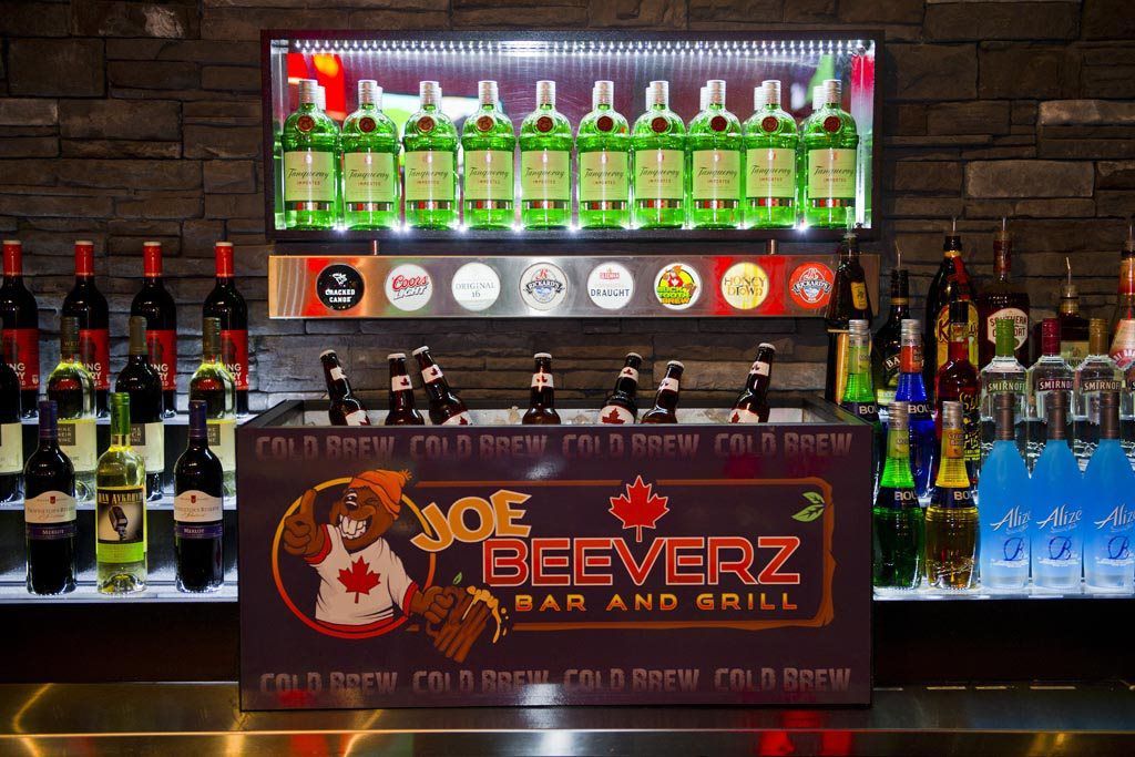Bar display with rows of beer bottles and illuminated Joe Beeverz Bar and Grill sign