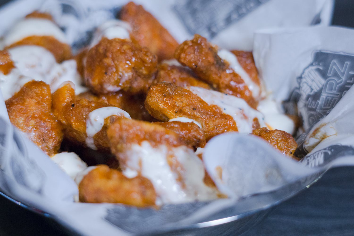 Saucy chicken wings in a basket lined with white paper
