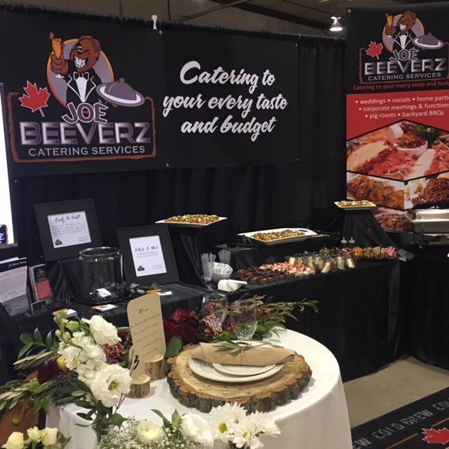 Eeverz Catering Services booth with black backdrop, food trays, and a decorative table display at an event.