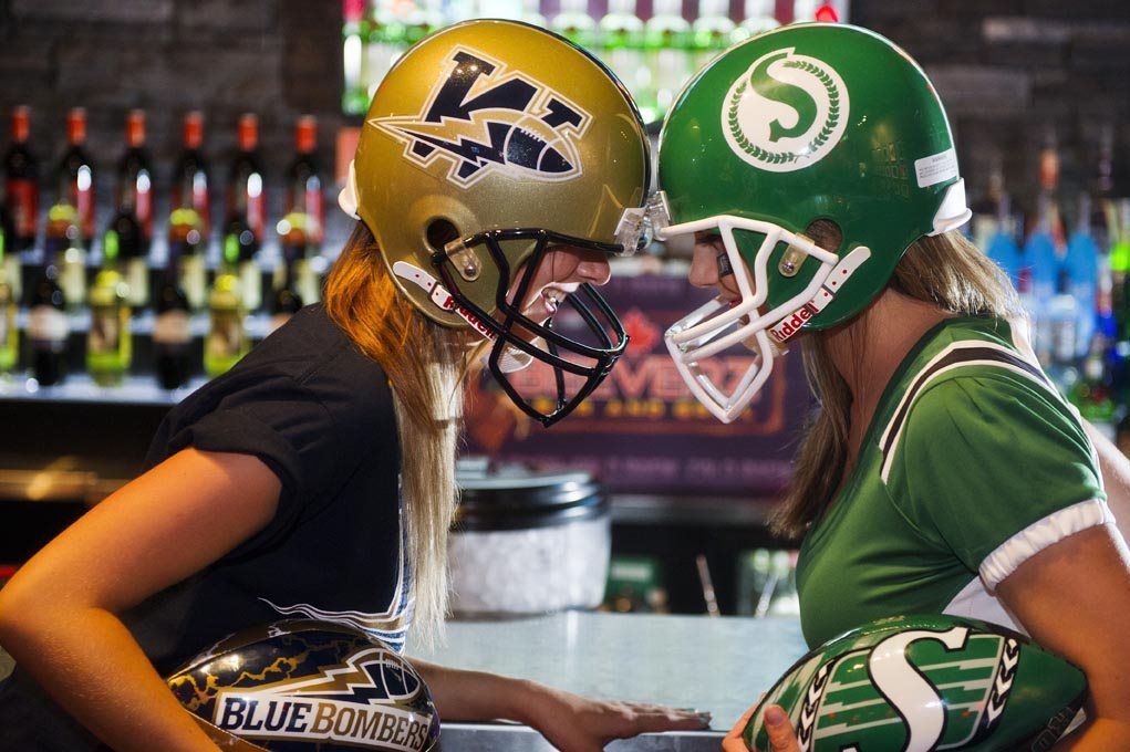 Two football players in helmets face off at a bar, with black and green jerseys.