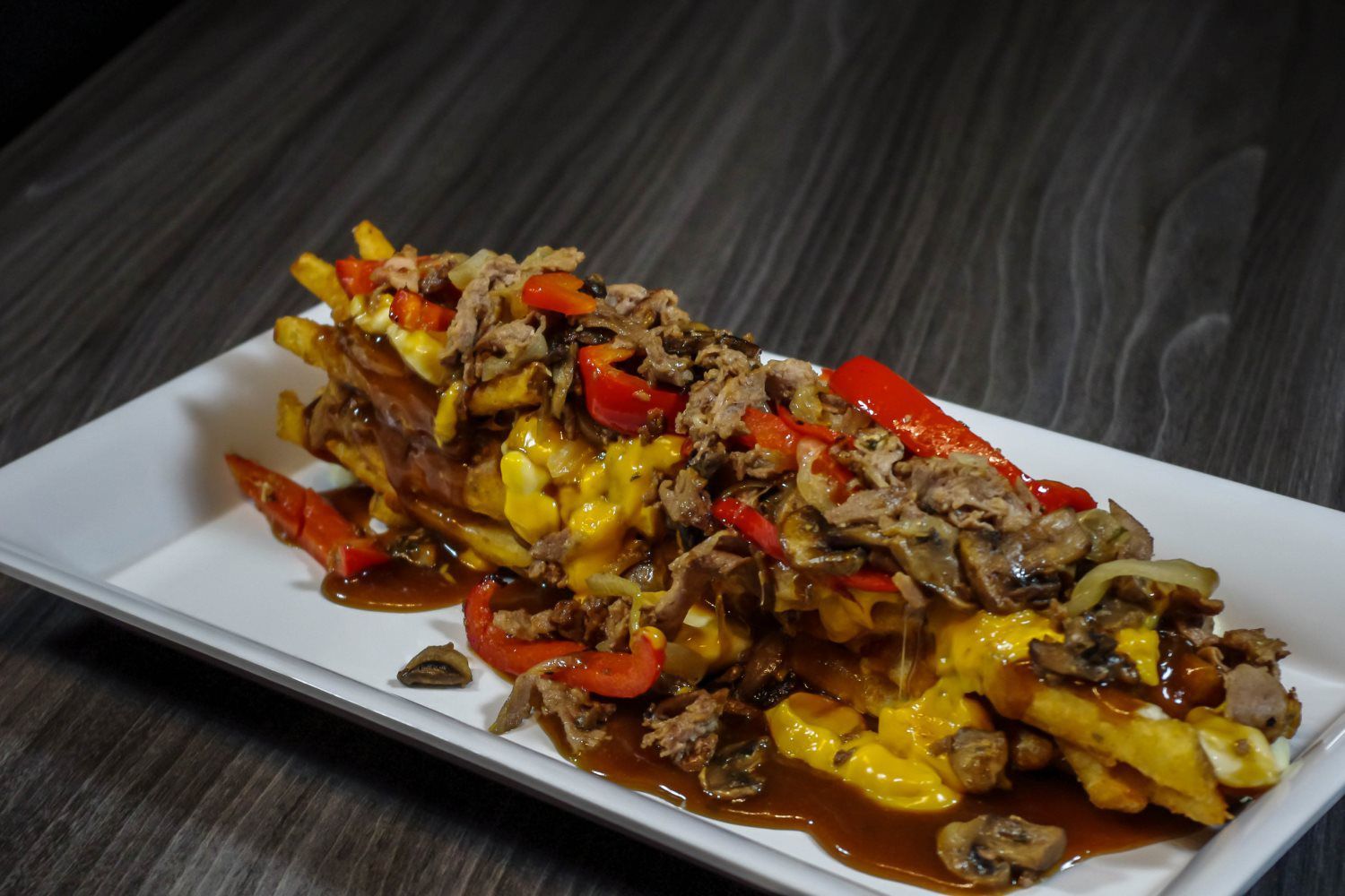 Plated stir-fried beef with peppers, onions, and melted cheese on a white dish