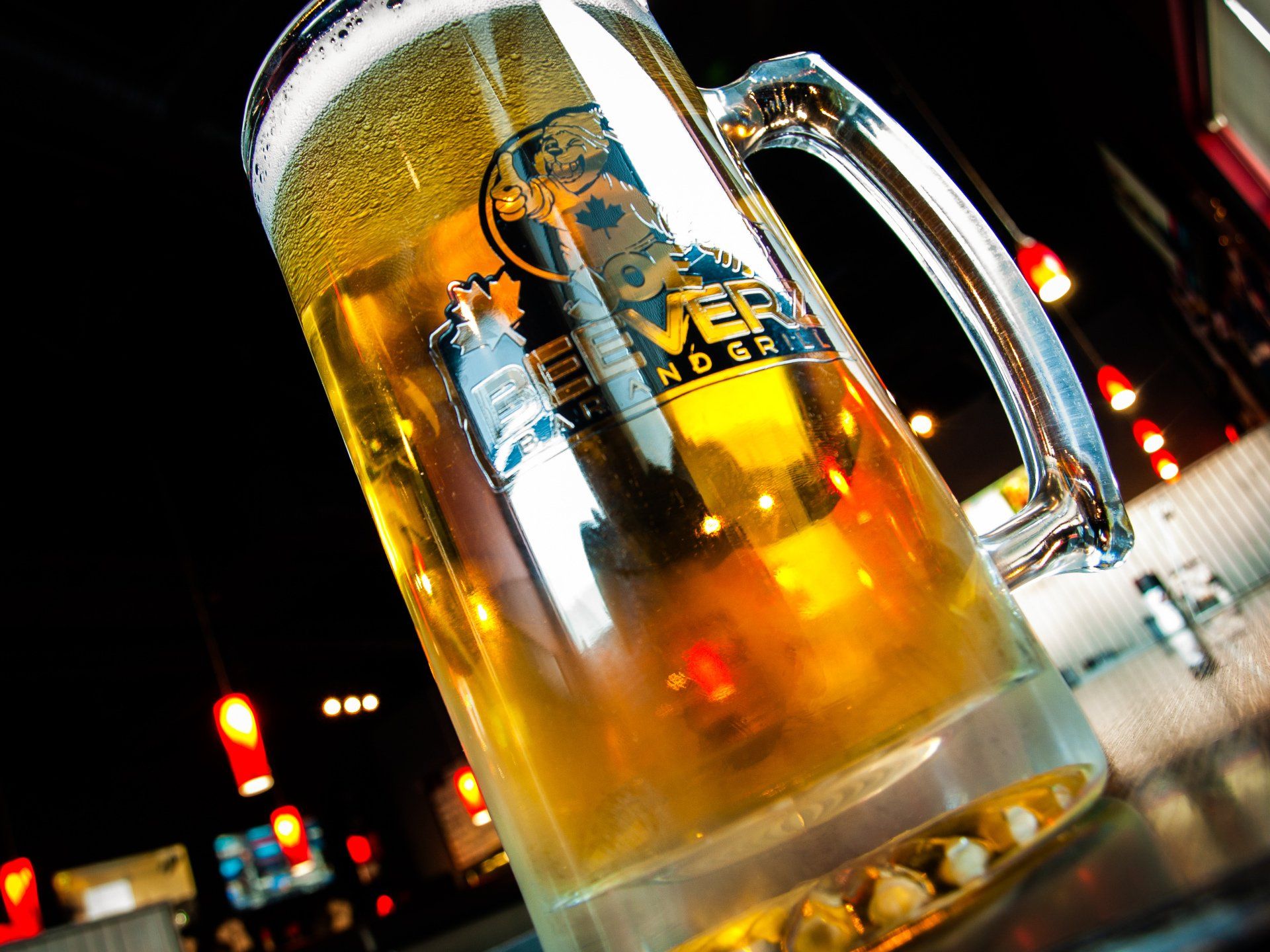 Close-up of a frosty beer mug with golden beer and blurred neon lights in the background