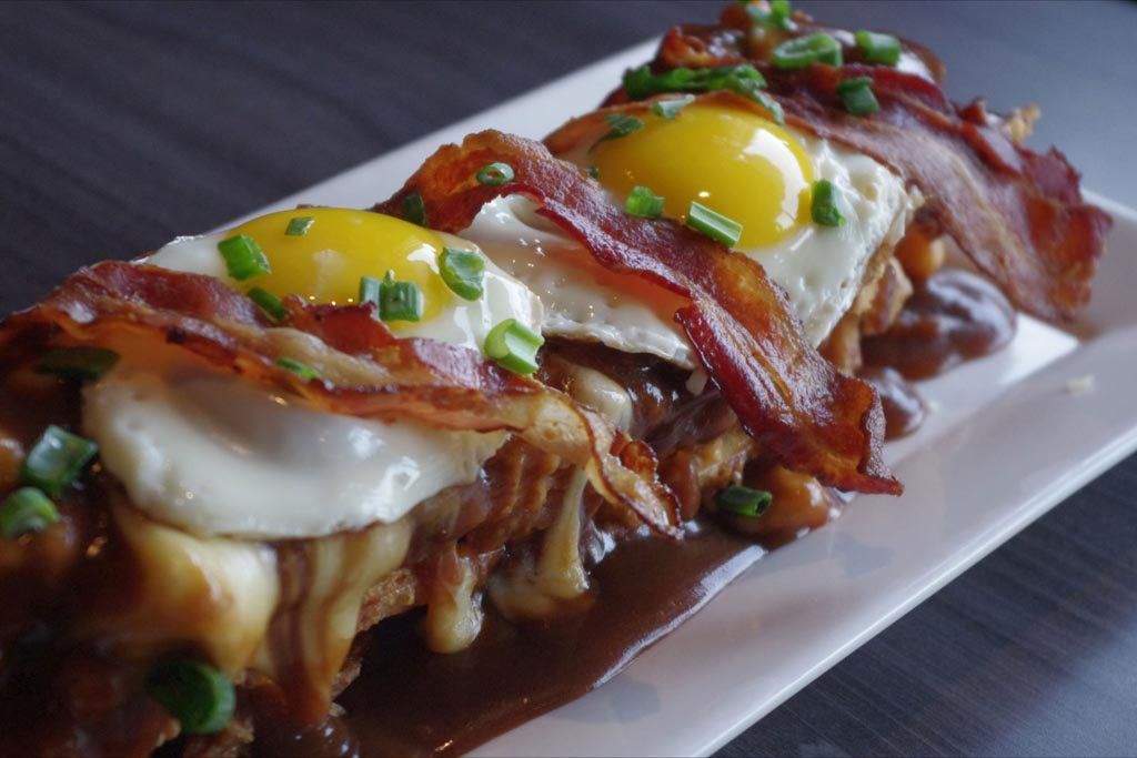 Baked eggs and bacon on toast, topped with green onions, served on a white plate
