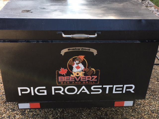 Black pig roaster cart with grill lid and “PIG ROASTER” text on the front