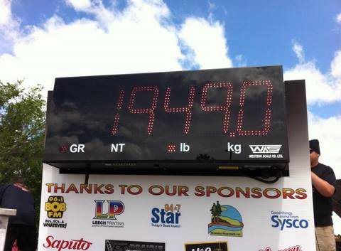 Digital race clock reading 19:49.70 above a sponsor banner under a cloudy sky.