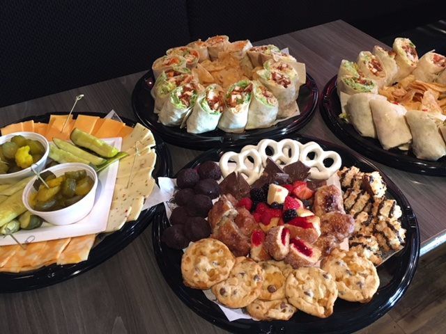 Assorted appetizers and finger foods arranged on black platters on a table