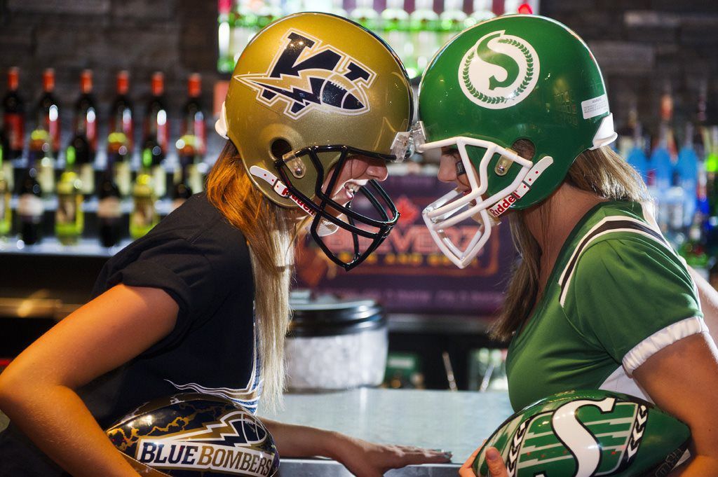 Two football fans in helmets face off at a bar, leaning toward each other at a counter.