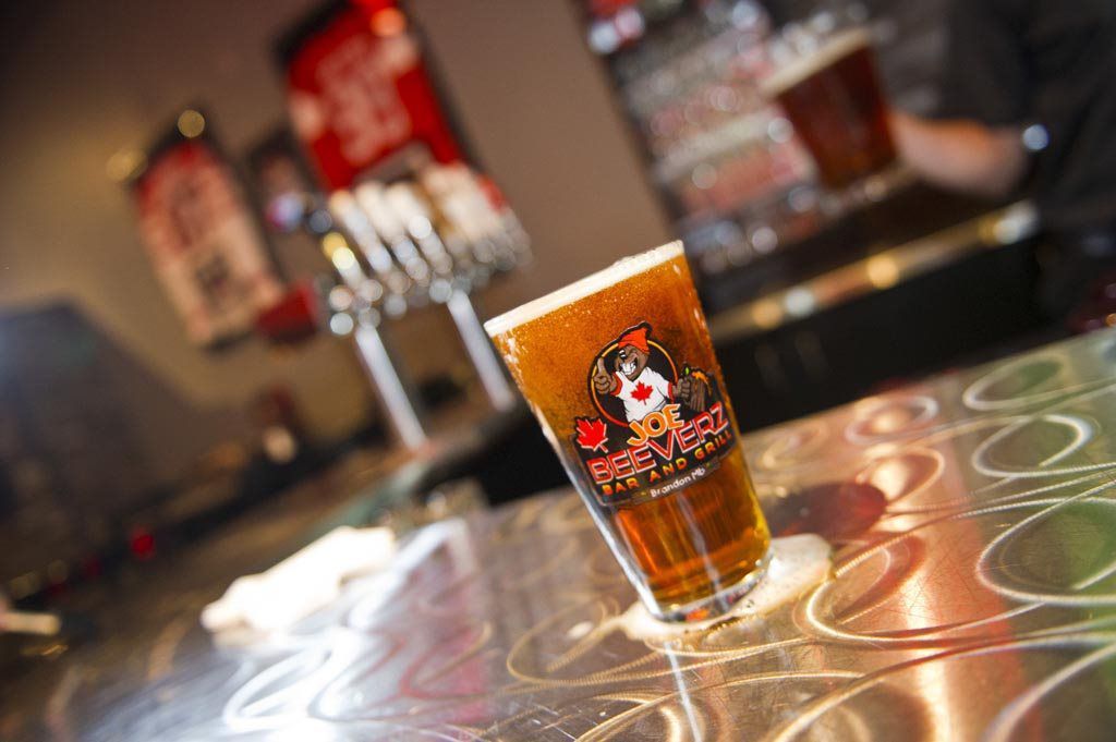 Branded pint glasses of amber beer on a reflective bar counter, with a blurred pub background