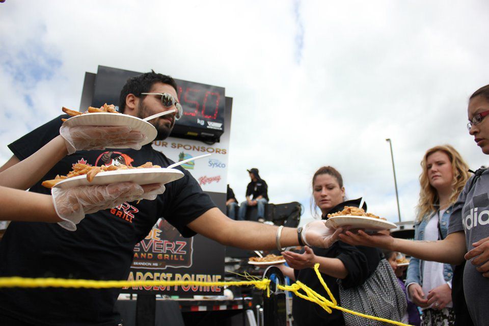 People handing out food over a yellow barrier at an outdoor event