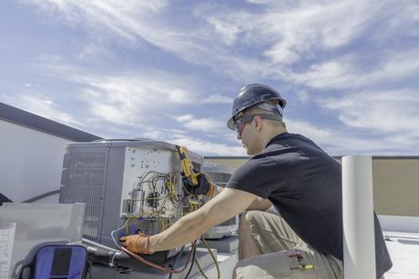 HVAC tech working on condenser wide angle