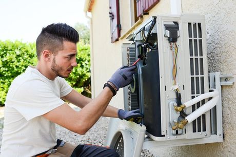 Handsome young man electrician installing air conditioning in client house
