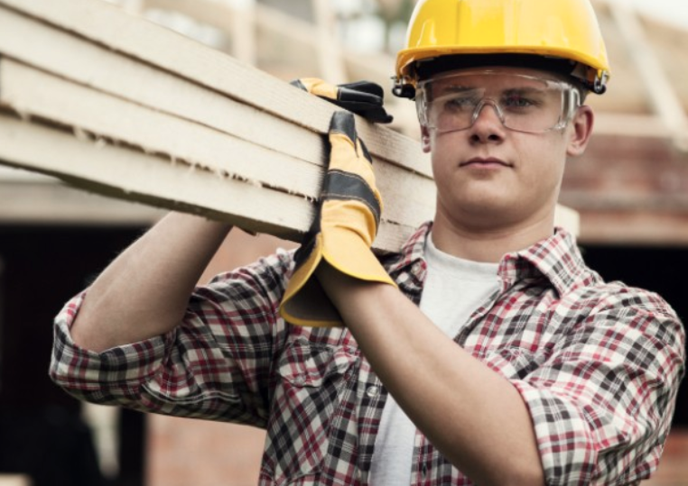 labourer carrying lumber on jobsite