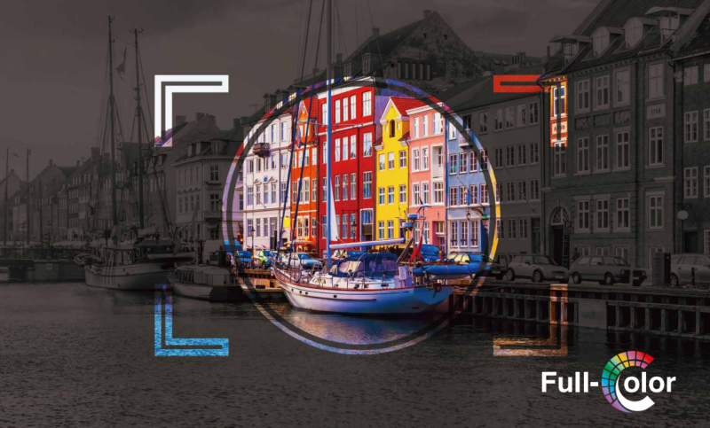 Colorful buildings in a circular frame stand out against a black and white harbor scene with a boat; the text