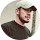 Portrait of a man wearing a beige cap and dark shirt against a white background