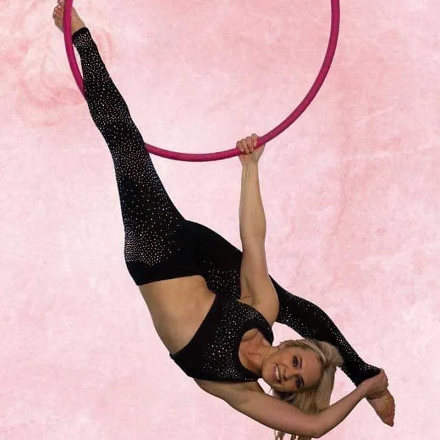 A woman is hanging upside down on an aerial hoop.