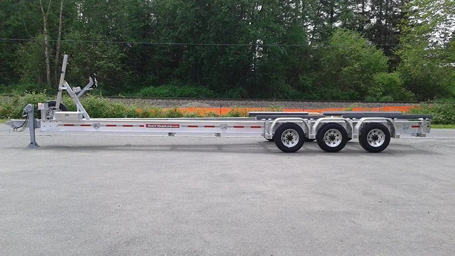 Silver boat trailer on paved surface, triple axle.