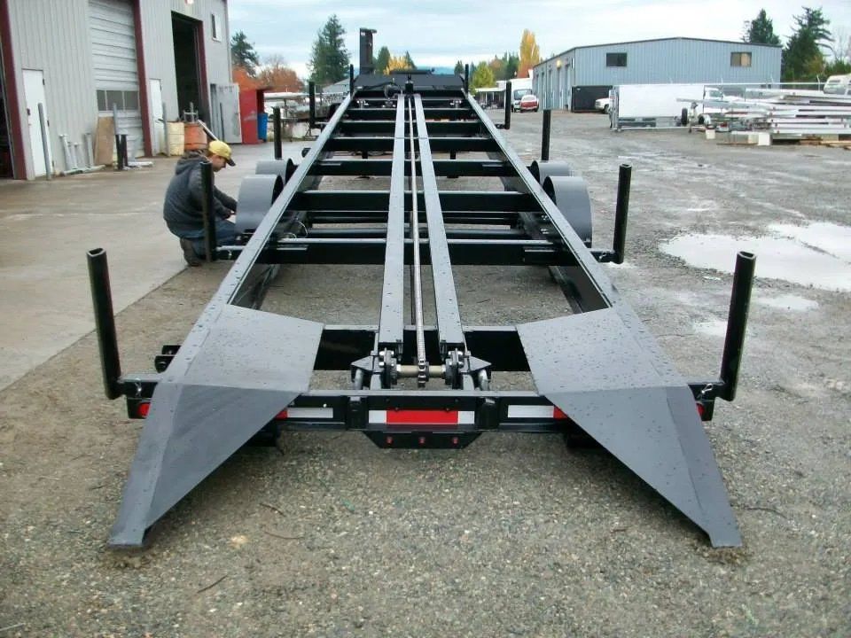 Black trailer with ramps, a person working on it outdoors.