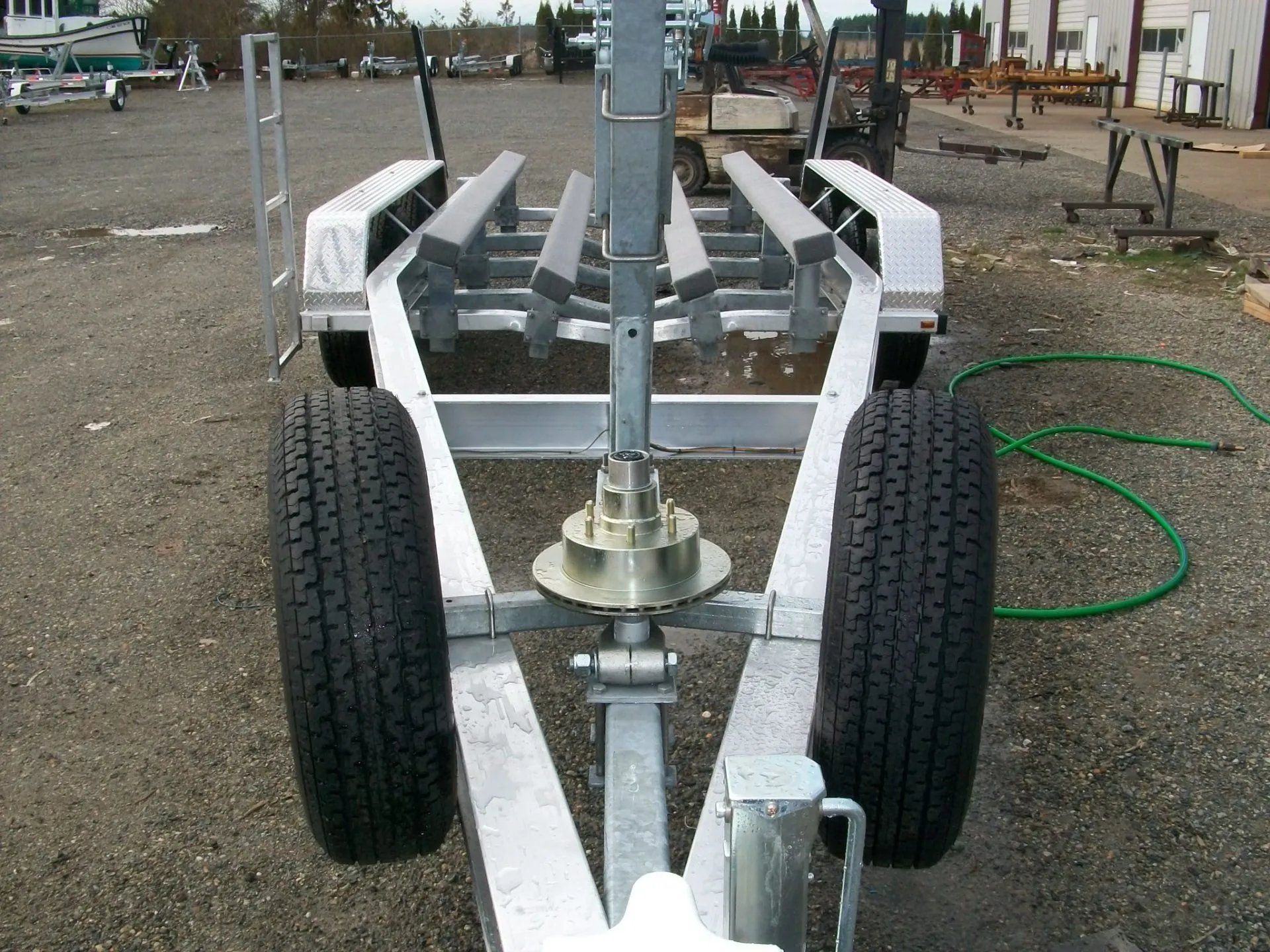 Boat trailer with two tires, rollers, and a metal frame on an outdoor surface.