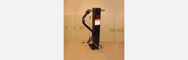 Black floor jack with a curved handle on a beige wall.