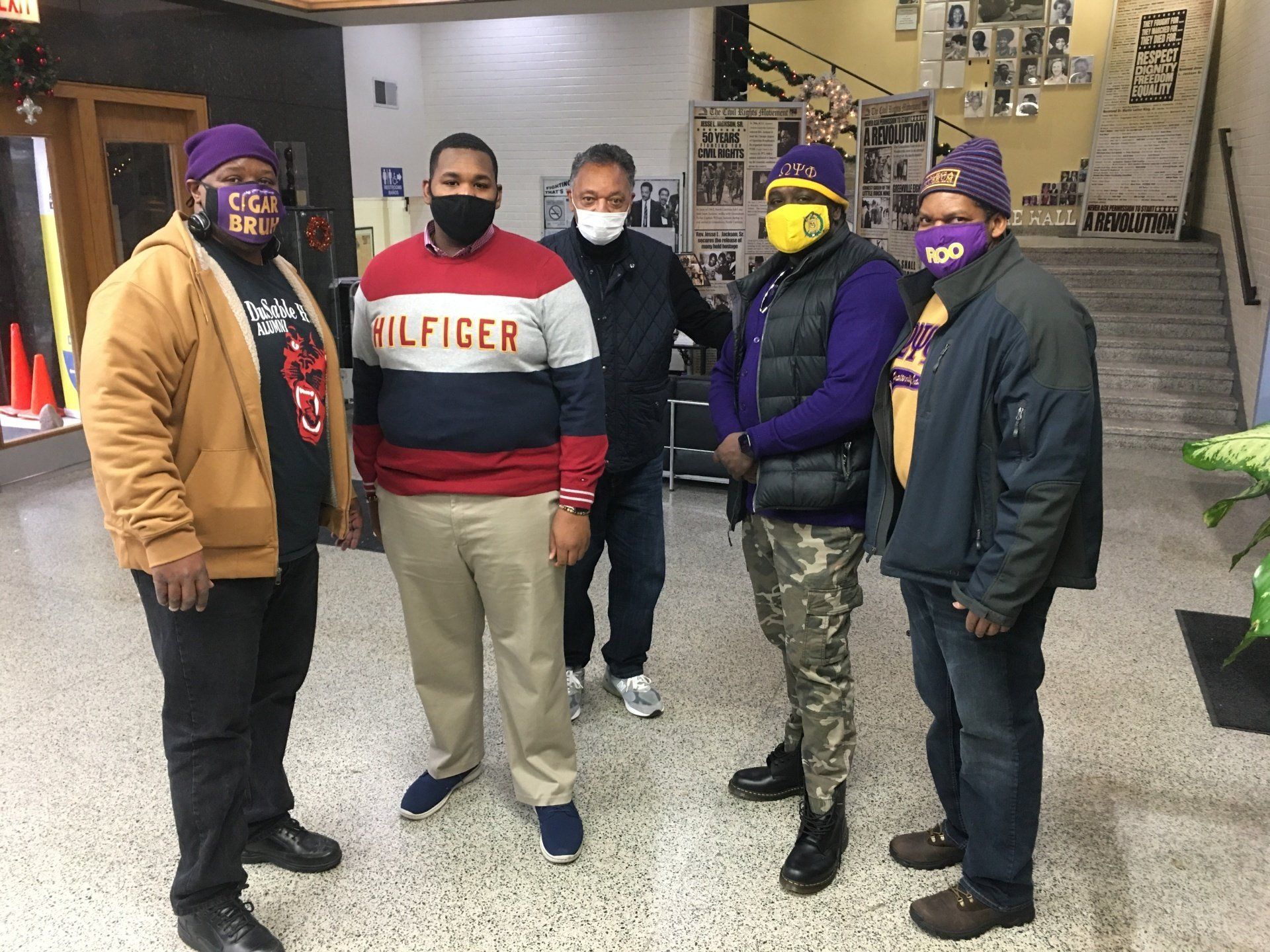A group of men wearing face masks are standing next to each other in a room.